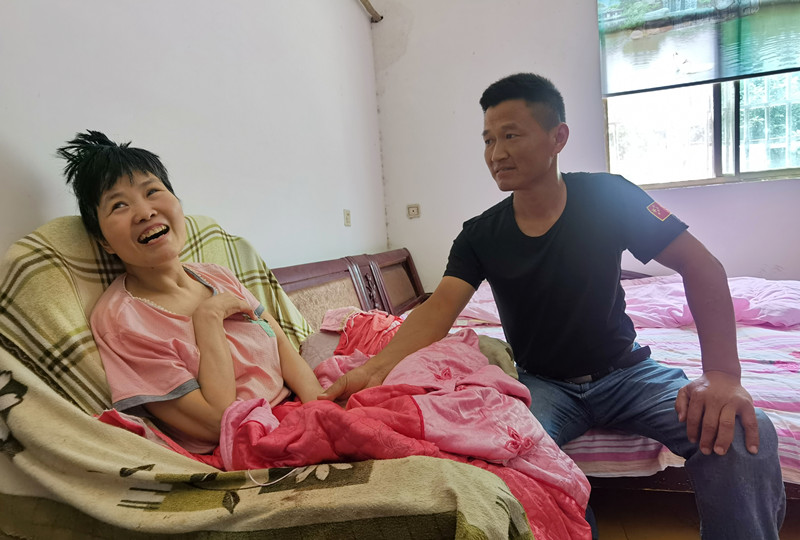 徐家龙将瘫痪在床的妻子抱到躺椅上.