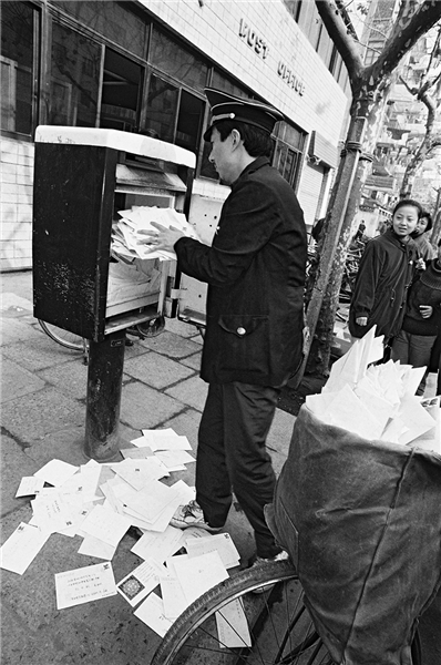 图说:邮递员打开塞满贺卡的邮箱 官方图