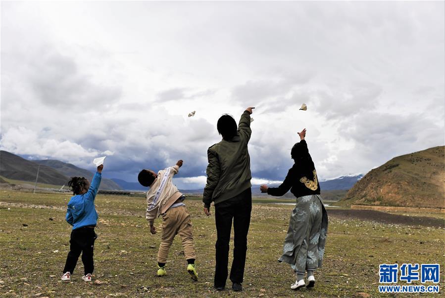 坚热益西(右二)在牧区和弟弟妹妹一起放飞纸飞机(7月13日摄).